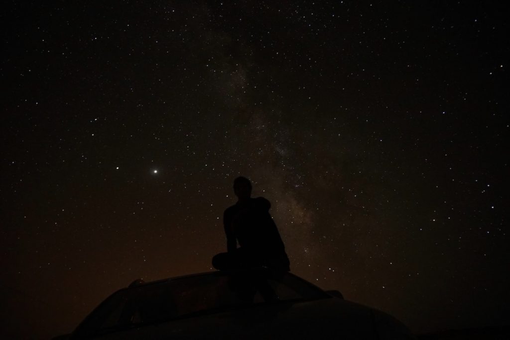silhouette of man sitting on car during night time